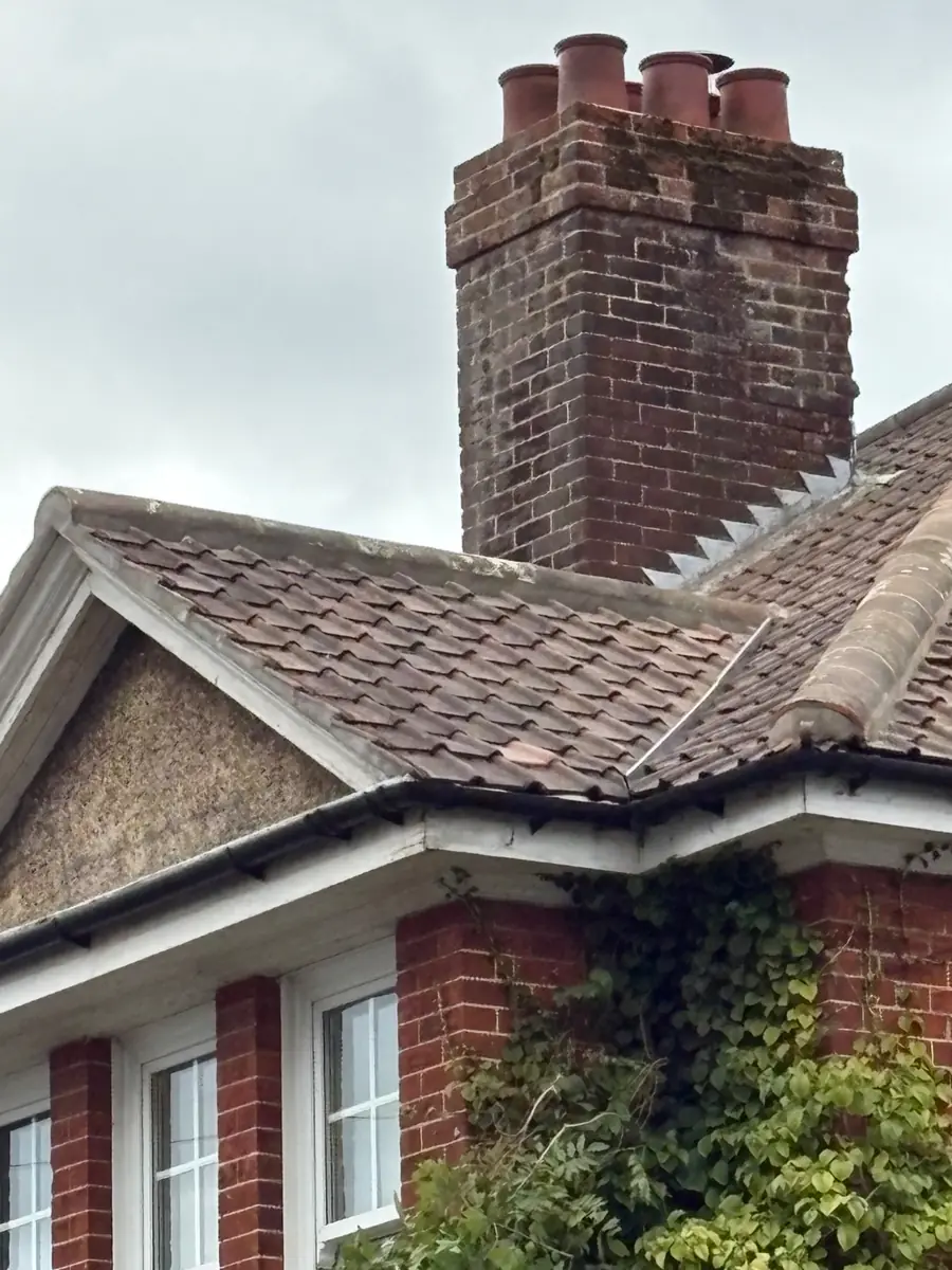 Chimney stack on a plain tiled roof with stepped lead flashing dressed into the brickwork