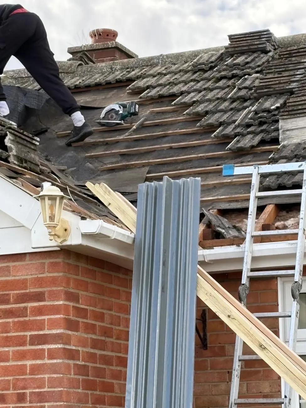 Old tiles and battens being removed above the eaves on an Ipswich terrace re-roof