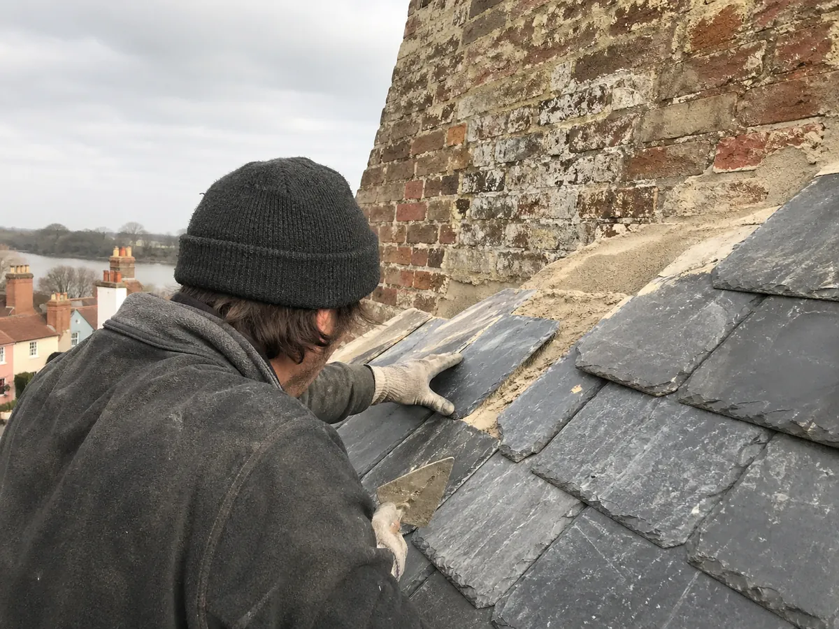 Roofer bedding slates against a chimney on a Woodbridge period property