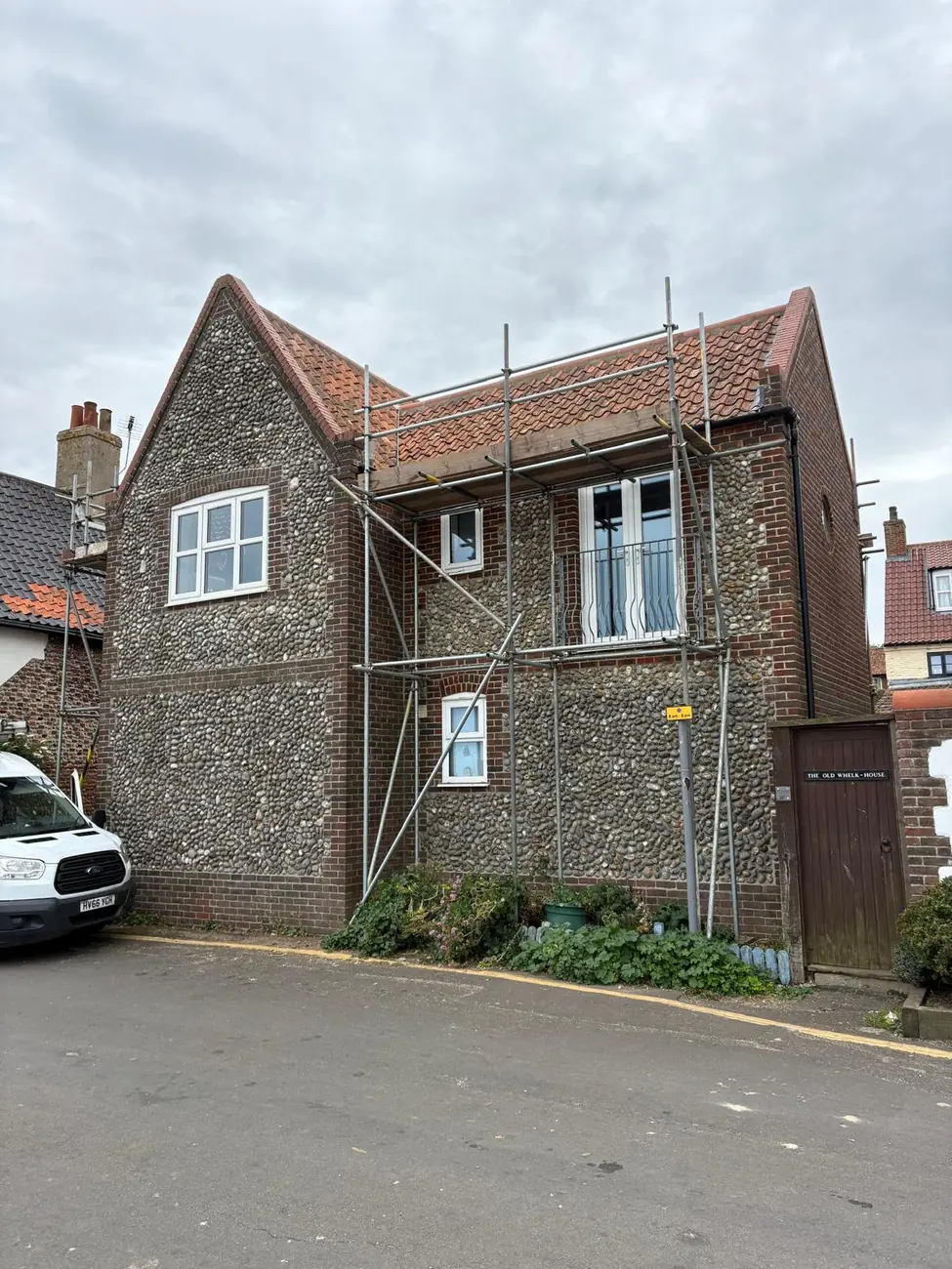 Scaffolded flint and brick seafront holiday home in Sheringham during a Stormproof re-roof